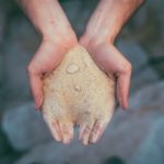 piasek do produkcji kryształków i koralików trzymany w rękach